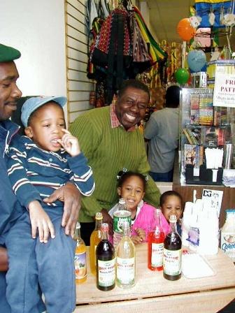 Oliver Samuels is all smiles as he samples the popular Jamaican Pure Bulk Syrup.  Joining Oliver l-r are Timex, and their little friends Andy, Melissa, and Stephen.  Jamaican food. Caribbean food. Oliver Samuels.